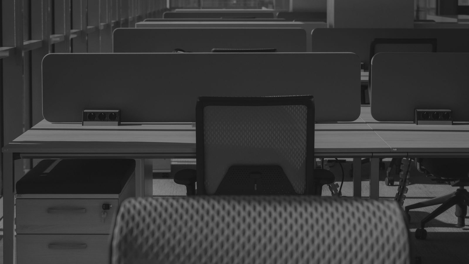 Rows of empty office desks and chairs in a vacant workspace