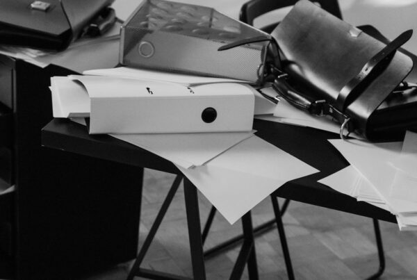 Binders, bags and loose papers sliding off a desk onto the floor