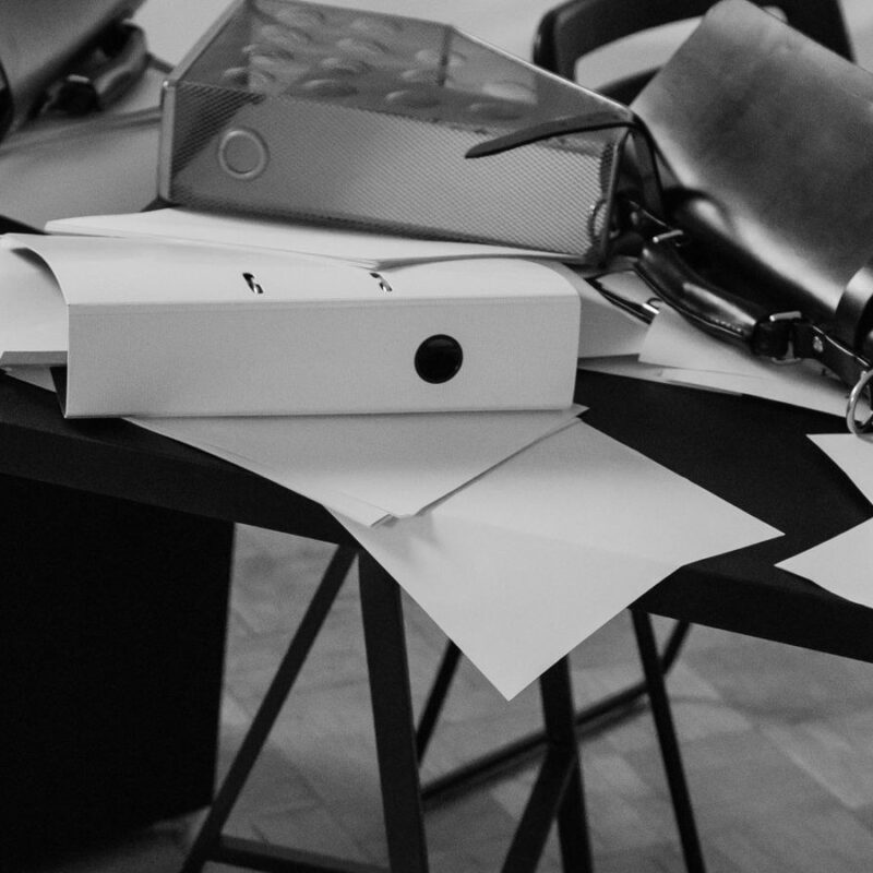 Binders, bags and loose papers sliding off a desk onto the floor