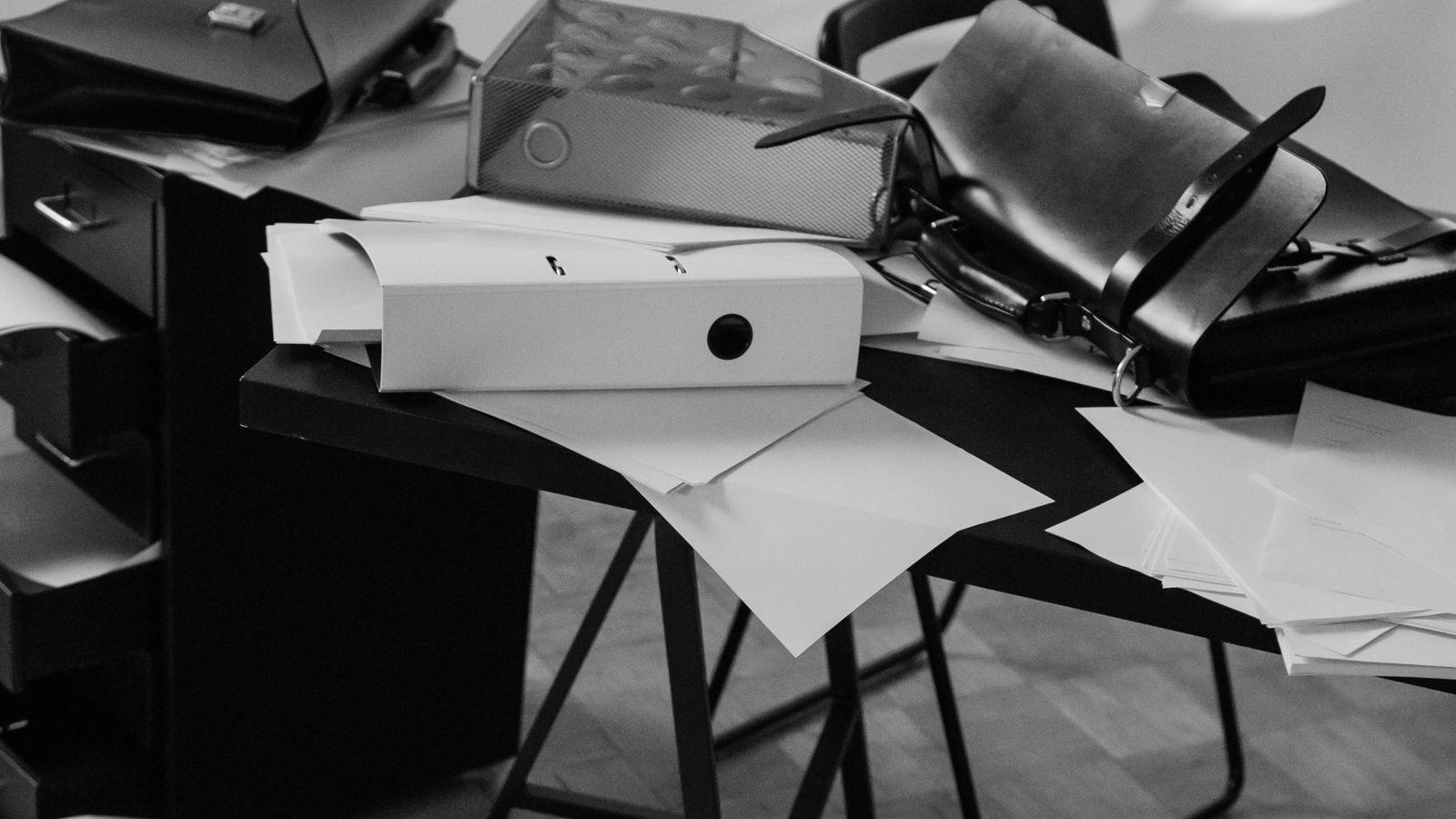 Binders, bags and loose papers sliding off a desk onto the floor