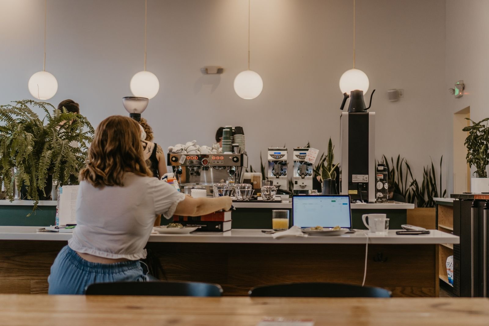 A woman working on a laptop at a coffee shop counter.