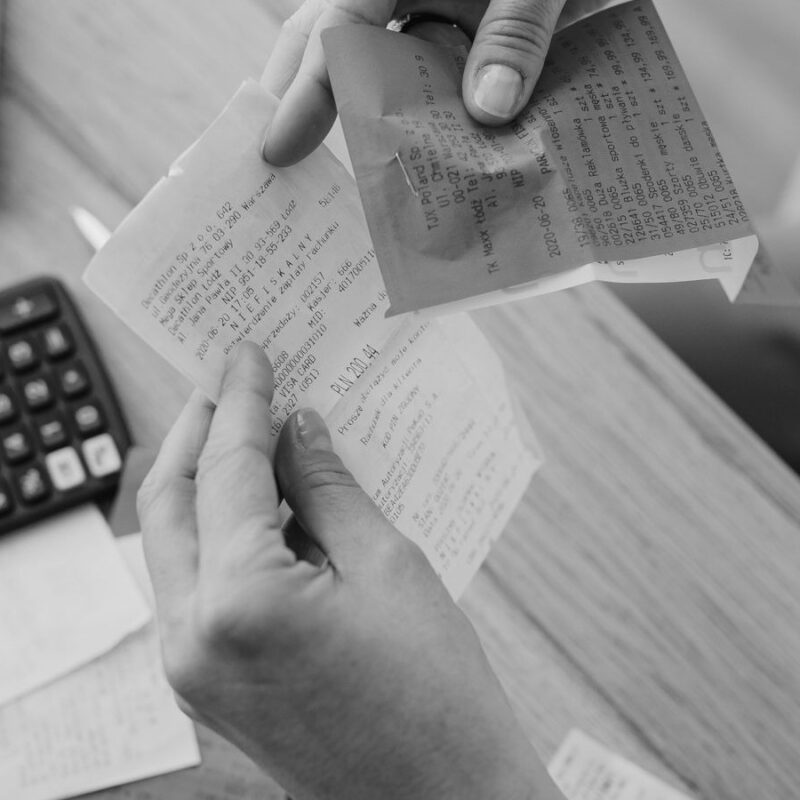 Hands holding paper receipts over a desk with a calculator and notes.