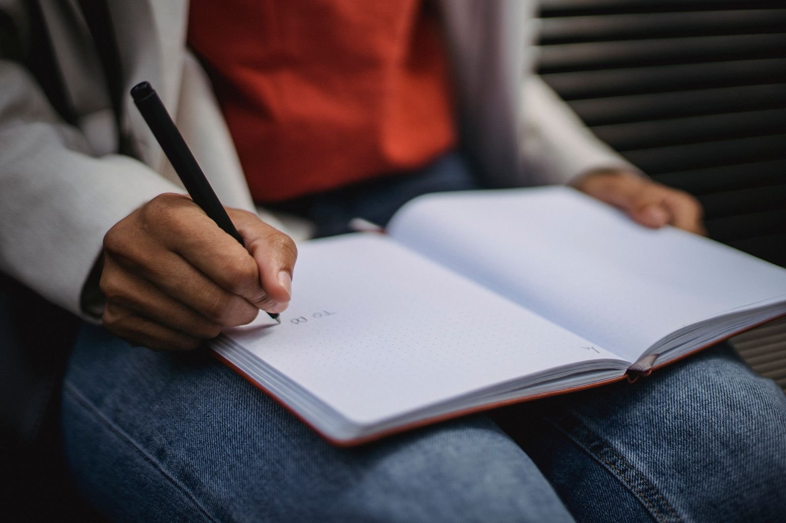 A hand writing with a pen in an open bound journal